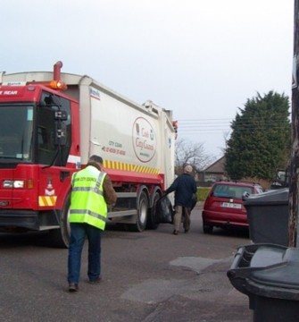 Ted Tynan brings bins to the truck under watchful eyes of Corpo inspector