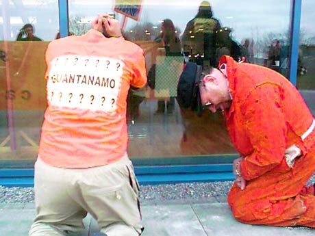 orange jumpsuits kneel outside Galway restaurant window to protest US ambassador