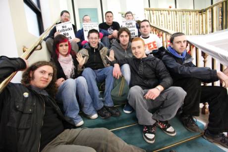 Members of FEE enter and unfurl a banner on the first floor of the Department of Finance