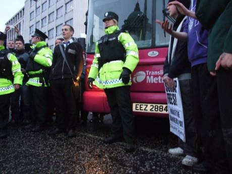 Protestors and PSNI officers in front of a bus which was stopped due to the protestors' sit-down protest on the road
