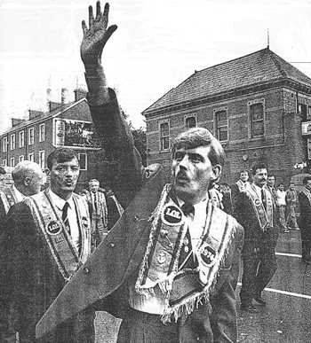 From The Independent 11 July 1997. Caption: “Triumphalism: Ormeau Road 1992, an Orangeman holds up five fingers as a parade passes a spot where five Catholics were shot dead by loyalist terrorists.”