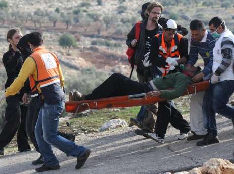 Head of Bil'in's Popular Committee, Iyad Burnat being stretchered away to safety from the Apartheid-Annexation Wall