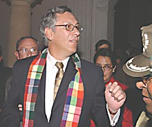 The Provisional President of Bolivia leaves the building with an indiginous scarf.