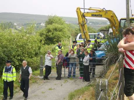 A digger under Garda escourt approaches the locked gates on Monday evening. 