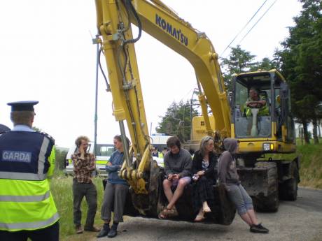 Protesters sit in the digger bucket. 