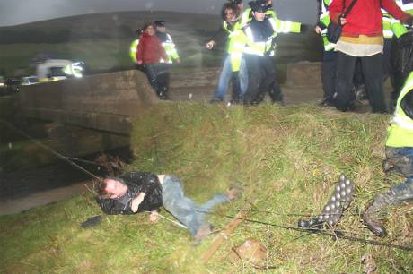 protesters are thrown over a barbed wire fence.