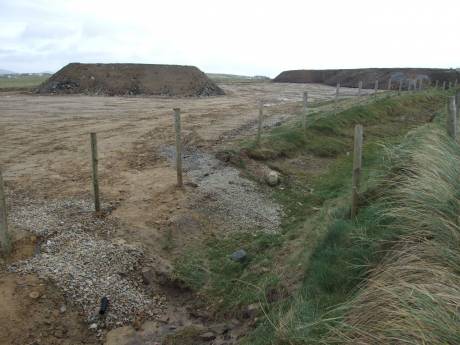 Mounds of rubble left on clifftop with run-off pipe in bottom left corner.