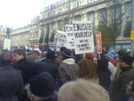 Placard urging people to educate themselves and understand how money works since thats the key to all of this.