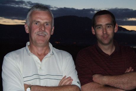 Luke Clarke (left), winner of category 3 in the captain's prize competition and Paddy Lawless runner-up overall.  They are standing on the balcony of Greenore golf clubhouse with the dark mass of Slieve Foy in the background.  Slieve Foy is the tallest pe